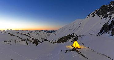 Illuminated tent in the snow on the Maedelejoch, dusk, near Kemptner hut, Allgaeuer Alps, Tyrol, Austria, Europe