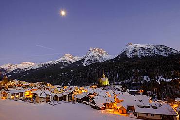 View of the town with Reformed church over the Inn in winter, dusk, Scuol, Graubuenden, Switzerland, Europe