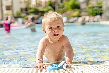 Cute, cheerful toddler playing with swimming goggle in the pool, Portugal, Europe