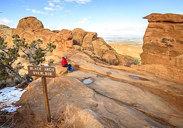 Tourist, young woman resting at Black Arch Overlook, viewpoint, sandstone cliffs, Devil's Garden Trail, Arches National Park, Utah, USA, North America