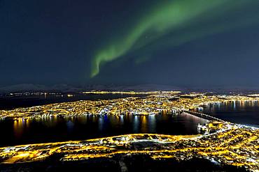 Illuminated city and aurora borealis above Fjellheisen, Tromsoe, Norway, Europe