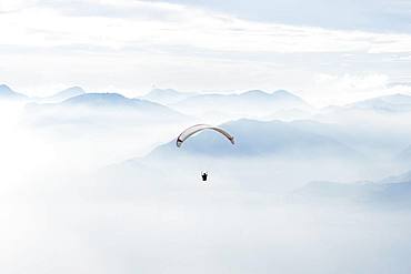 Paragliding over the mountains in clouds near Malcesine at Lake Garda, aerial view, Veneto, Italy, Europe