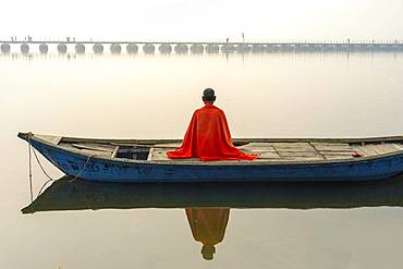 Sadhu with red shawl on a boat on the Ganges river at sunrise, Allahabad Kumbh Mela, world's largest religious gathering, Uttar Pradesh, India, Asia