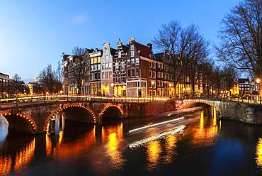 Evening mood, light tracks, boat cruises through canal with bridge, Keizersgracht and Leidsegracht, canal with historic houses, Amsterdam, North Holland, Netherlands