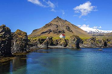 Lonely house on the basalt coast near the harbour, behind the mountain Stapafell and the glacier Snaefelljoekull, Arnarstapi, peninsula Snaefellsness, Iceland, Europe