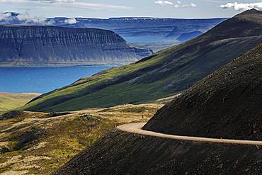 Gravel road meanders through volcanic landscape, near Hrafnseyri, Westfjords, Iceland, Europe