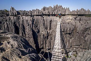 Tourist on suspension bridge over gorge in rugged limestone rocks, limestone rocks in Tsingy de Bemaraha National Park, Madagascar, Africa