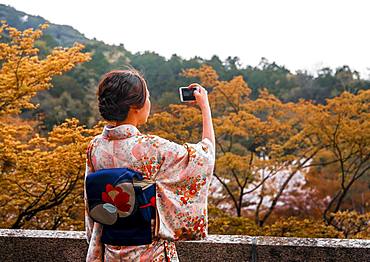 Japanese woman dressed with kimono, photographed with a mobile phone, at Kiyomizu-dera Temple, Higashiyama, Kyoto, Japan, Asia