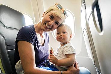 Mother with baby playing in a passenger airplane, Poland, Europe