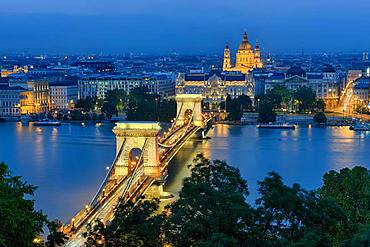 Chain bridge with Gresham Palace and St. Stephen's Basilica, illuminated, dusk, Budapest, Hungary, Europe