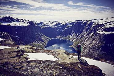 Young woman climbing to Trolltunga, view into the fjord, Sorfjord, near Odda, Norway, Europe