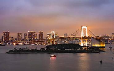 View of skyline with skyscrapers and illuminated Rainbow Bridge in the evening, Odaiba, Tokyo, Japan, Asia