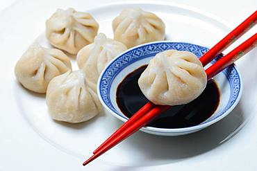 Dim Sum, filled dumplings and bowl with soy sauce, red chopsticks, Germany, Europe