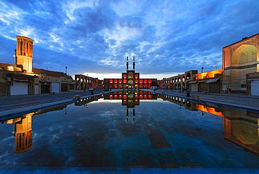 Amir Chaqmaq complex facade illuminated at sunrise and reflecting in a pond, Yzad, Yazd province, Iran, Asia