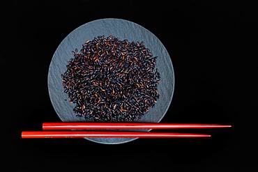 Black rice in bowl with red chopsticks, Germany, Europe