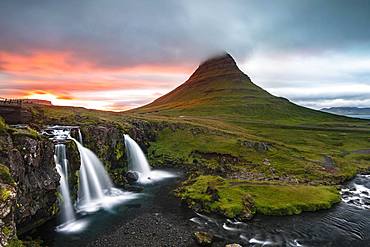 Waterfall Kirkjufellsfoss and mountain Kirkjufell, sun breaks through clouds, Grundarfjoerdur, Snaefellsnes peninsula, Snaefellsnes, Vesturland, Iceland, Europe