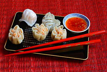 Dim Sum, filled dumplings on tray with red chopsticks and chilli sauce, Germany, Europe