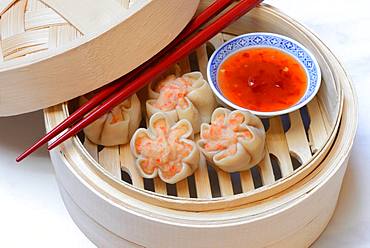 Dim Sum, filled dumplings with chopsticks and chilli sauce in steam baskets, Germany, Europe