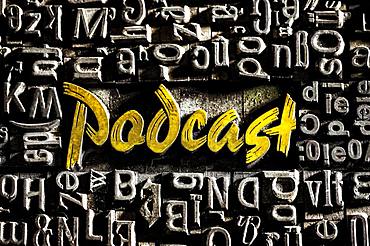 Old lead letters with golden writing show the word podcast