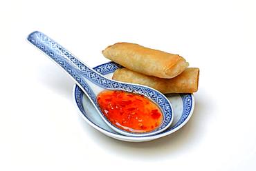 Chilli sauce in Asian spoon and mini spring rolls, Germany, Europe