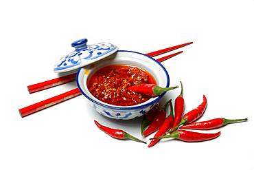 Crushed chilli peppers in oil in shell and red chopsticks, Germany, Europe