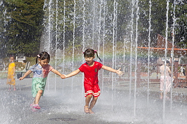 Girls, 4 and 6 years, walking through jets of water from a well, Odongdo Island, Yeosu, Jeollanam-do, South Korea, Asia