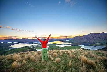 Hiker stretches his arms in the air, panoramic view of Wanaka Lake and mountains at sunset, Rocky Peak, Glendhu Bay, Otago, South Island