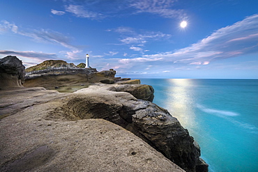 Lighthouse at full moon on the cliffs of lava rock at Castlepoint, Masterton, Wellington, New Zealand, Oceania