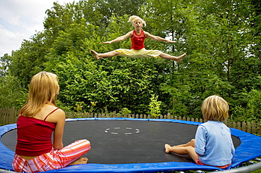 Girls jumping on the trampoline in the garden, Austria, Europe