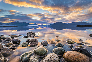 Light beam of golden cloud atmosphere over Lake Te Anau, in the back mountain ranges of the Stuart Mountains and Franklin Mountains, in the front round stones, Fjordland National Park, Te Anau, Te Anau, Southland, New Zealand, Oceania