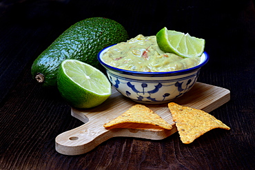 Bowl with guacamole, avocado, lime and tortilla chips, Germany, Europe