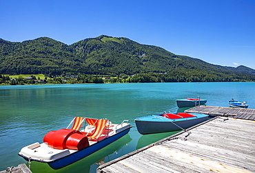 Pedal boat and electric boats at the landing stage on the lake promenade, behind it the Filbling, Fuschlsee, Fuschl am See, Salzkammergut, Province of Salzburg, Austria, Europe