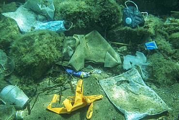 Discarded used medical face mask lies on the seabed together with other plastic waste, Becici, Budva region, Montenegro, Europe