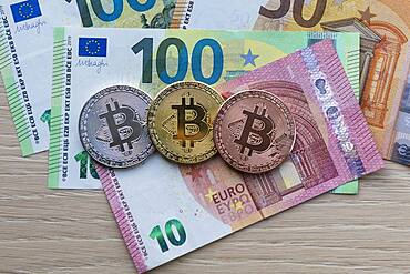 Symbol image digital currency, physical coin Bitcoin, silver, gold, bronze, on euro banknotes