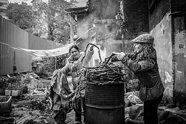 Street scene in an old town quarter of Chongqing. Women are smoking homemade sausages. These districts are gradually being demolished to make room for new residential areas with high-rise buildings, Chongqing, China, Asia