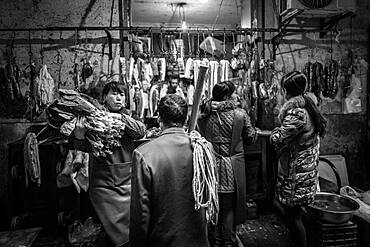 Day labourer in front of a butcher's shop in a market in the centre of Chongqing, from his wages he can only buy the cheap pieces of meat, Chongqing, China, Asia