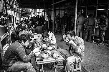 Worker having lunch at a stall in a market in the center of Chongqing, from his wages he can only buy the cheap pieces of meat, Chongqing, China, Asia