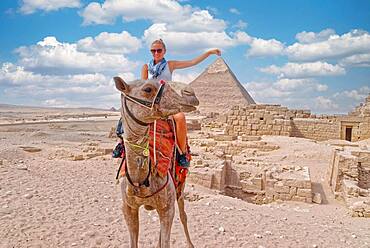 Woman on a camel in front of a pyramid, Giza, Cairo, Egypt, Africa