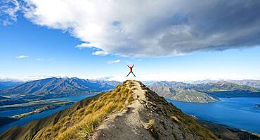 Hiker takes a skydive, views of mountains and lake from Mount Roy, Roys Peak, Lake Wanaka, Southern Alps, Otago, South Island, New Zealand, Oceania