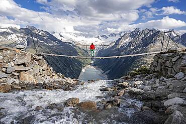 Hiker, woman on suspension bridge at the Olpererhuette, Schlegeis reservoir, Schlegeis reservoir, Zillertal Alps, Schlegeiskees glacier, Zillertal, Tyrol, Austria, Europe