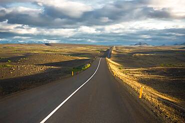 Road in the evening light runs through vuclan plateau with lava rock in the Krafla, Myvatn region, Skutustaoir, Norourland eystra, Iceland, Europe