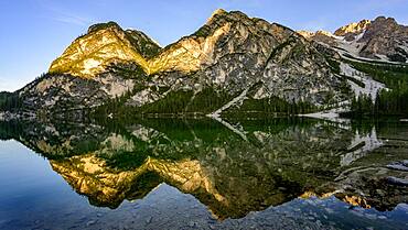 Mountains in the evening light are reflected in Lake Prags Lake, Lago di Lake Prags, Lake Prags Valley, Lake Prags, Dolomites, South Tyrol, Alto Adige, Italy, Europe