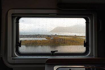 View from rainy campervan kitchen window on Flakstad beach, Flakstad, Lofoten, Norway, Europe