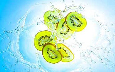 Slices of the kiwi with water splashes, light blue background