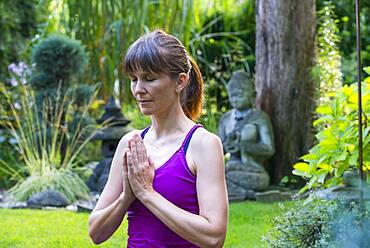 Woman doing yoga in garden, Bavaria, Germany, Europe