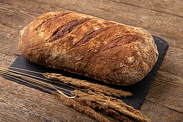 Freshly baked bread on black slate, wooden table