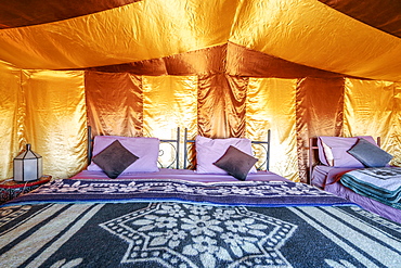 Three beds inside elegant tent set on Sahara desert, Morocco, Africa