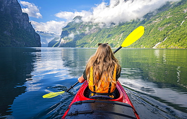 Young woman paddling in a kayak, Geirangerfjord, near Geiranger, Norway, Europe