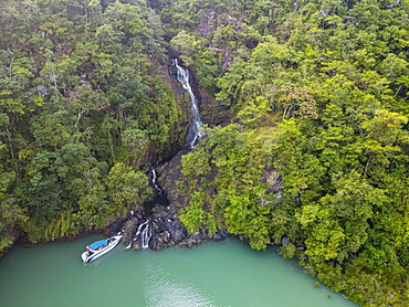 Aerial of a waterfall dropping right in the ocean on Dome island, Mergui or Myeik Archipelago, Myanmar, Asia