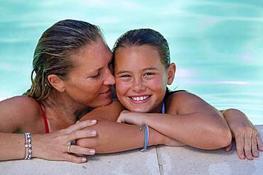Woman with daughter at pool, in water, italy